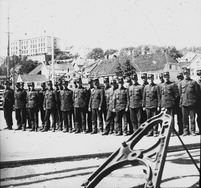 Fotografi av soldater oppstilt på rekke, ved havn