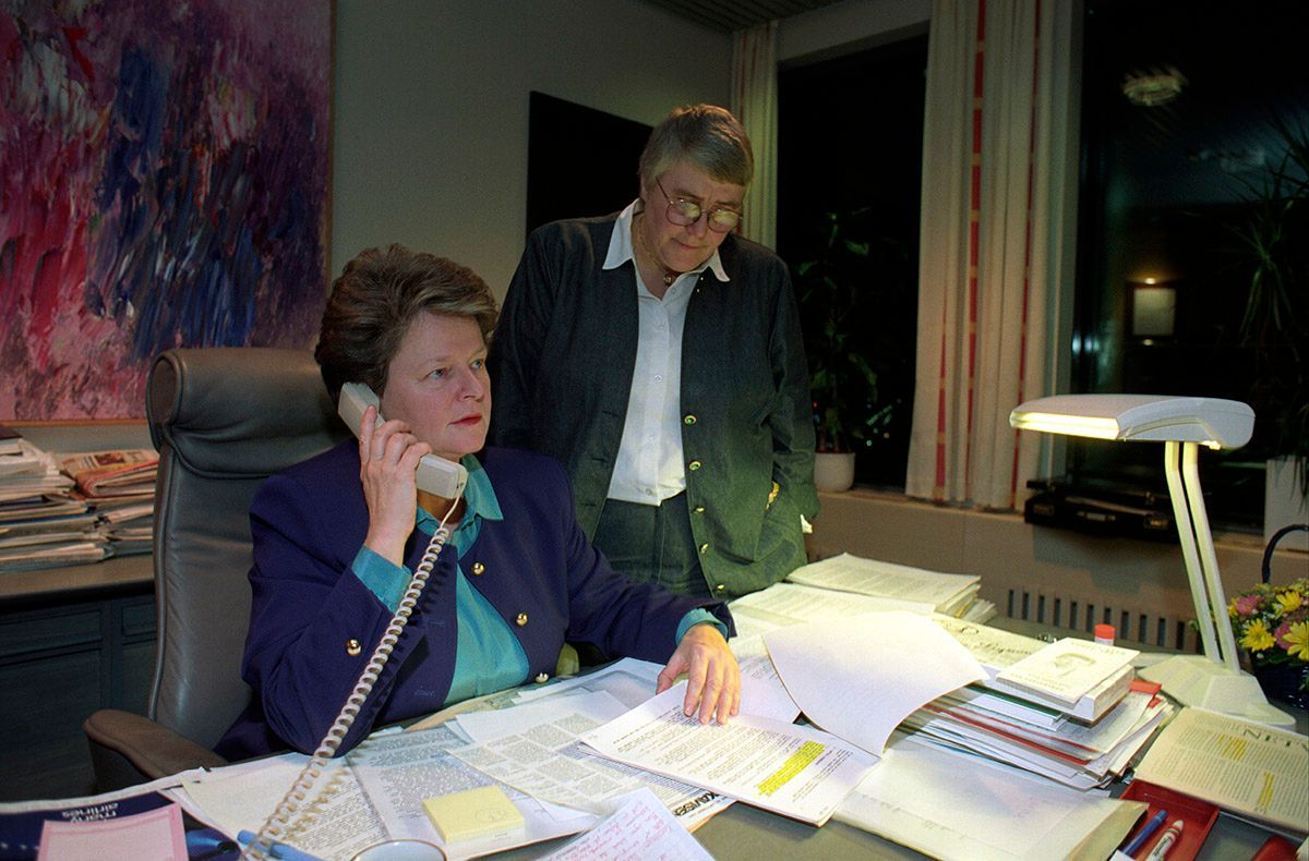 Kontor, statsminister Gro Harlem Brundtland ved skrivebord, held telefon mot øyret, ein person, Oddrun Pettersen, står ved sida av statsministeren, 