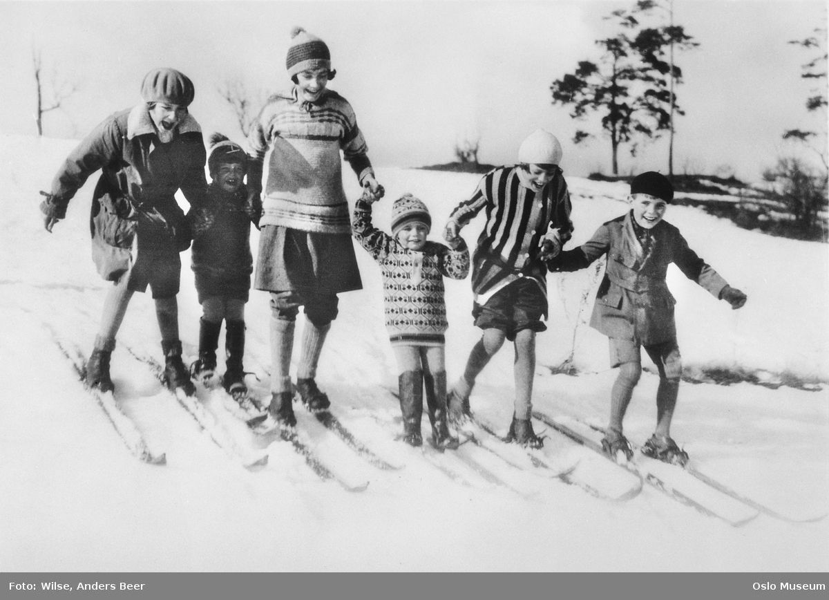 En liten gruppe barn og en voksen leker på ski. 