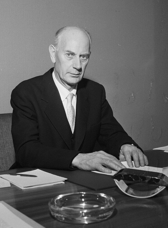 Foto av Einar Gerhardsen sittende ved pult med papirer i hendene