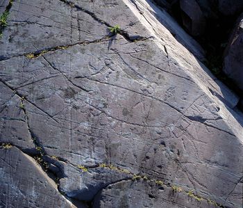 Helleristning fra Kåfjord i Alta fra om lag 4800–3700 f.Kr. Ristningen er av mennesker som løfter en båt og kan tolkes som en gjengivelse av et ritual. Hvorfor havet var så viktig for steinaldermenneskene, kan du lese om her . Foto: Knut Helskog/Tromsø Museum – Universitetsmuseet/ CC BY-NC-ND 3.0