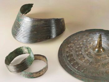Armringer, halskrage og tutulus (belteplate) i bronse, funnet i en gravhaug ved Rægje på Sola i Rogaland. Kunstnerisk utformede smykker og våpen av bronse ble brukt som statusmarkører og fulgte ofte eieren i graven i perioden 1500–1100 f.Kr. Les mer om hvordan bronse ble brukt i bronsealderen . Foto: Terje Tveit/Arkeologisk museum, Universitetet i Stavanger/ CC BY-NC-ND 3.0
