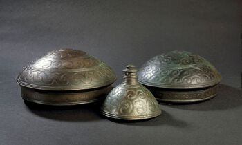 Disse draktsmykkene ble funnet i en steinur på en holme i Vannsjø i Østfold og er blant de flotteste depotfunnene som er gjort i Norge. Her er to hengekar og en tutulus (en belteplate) av bronse. Les mer om ofring av gjenstander i bronsealderen . Foto: Eirik Irgens Johnsen/Kulturhistorisk museum, UiO/ CC BY-NC 3.0