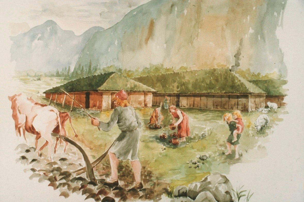 Akvarell av bosetning i landskap: Tre langhus i bakgrunn, kvinner arbeider med krukker og planter, mann i forgrunn med okse og plog