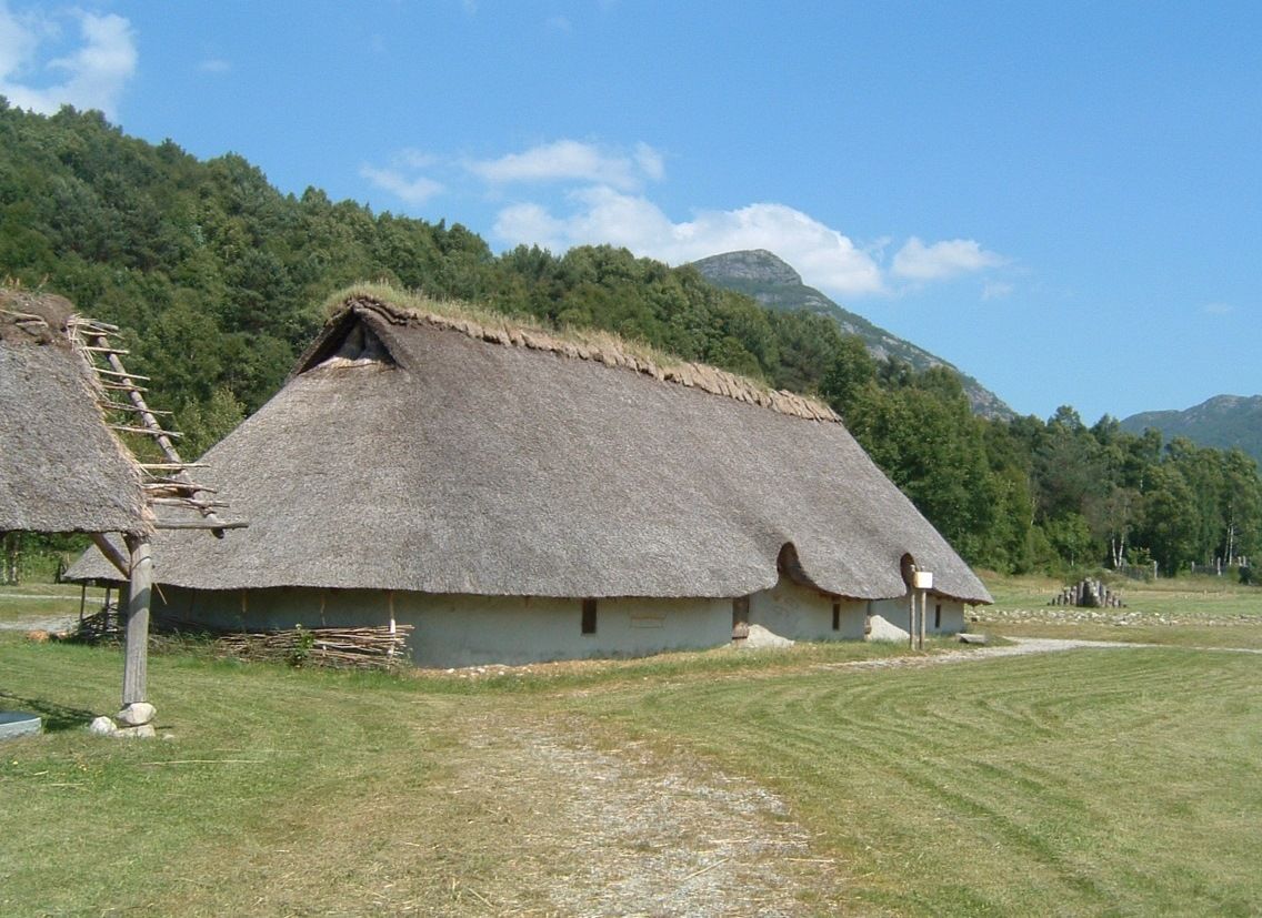 Fotografi av rekonstruert bronsealderhus: lave vegger og høyt tak