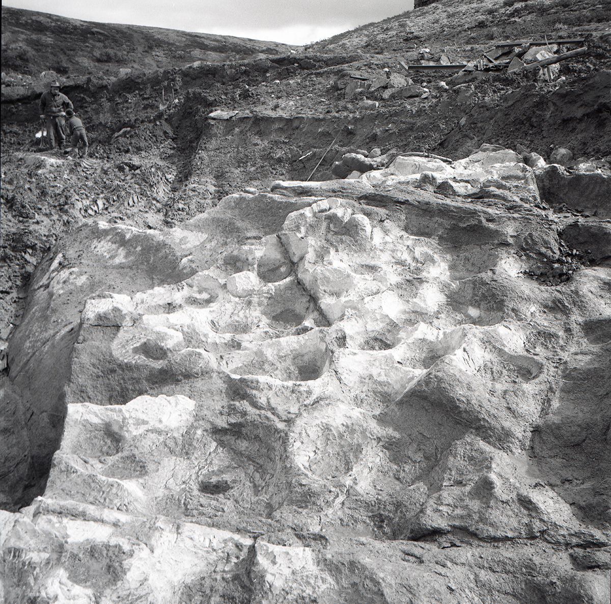Scene fra klebersteinsbruddet. To mennesker i bakgrunn, svart-hvitt-foto