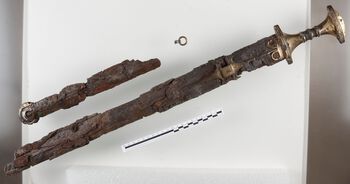 Tveegget sverd fra et gravfunn i Melhus, Sør-Trøndelag. Sverdet er av jern og bronse, og er komplett i hele sin lengde, ca. 1,02 m. Rikt dekorert med dyrehoder, bånd og buer. Den lille ringen i bronse hører til sverdskjeden. Foto: Ole Bjørn Pedersen, NTNU University Museum CC BY-SA 4.0