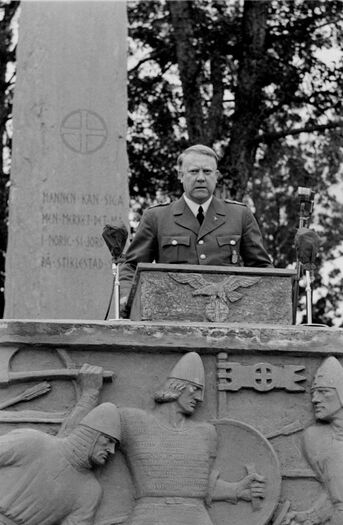 Allerede i 1934, ett år etter partiet ble stiftet, hadde Nasjonal Samling sitt første stevne på Stiklestad. Å knyte partiet og partiets ideologi an til norsk historie og norsk storhet var helt sentralt for partiledelsen. I 1944 ble det bygd et storstilt monument med talerstol på Stiklestad, i ettertiden kjent som NS-monumentet. Billedkunstneren bak anlegget var Wilhelm Rasmussen. Her ser vi Vidkun Quisling holde tale ved åpningen av monumentet på olsok i 1944. Foto: Per Renbjør/Levanger Fotomuseum