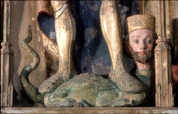 Nærbilde av den gåtefulle underliggeren. Les mer om helgenfigurene i kirkerommet . St.Olav-figur stående på en drage med menneskeansikt. &amp;#160;I et alterskap fra Andenes kirke, Andøy i Nordland. Foto: Mari Karlstad / Tromsø Museum, UiT /&amp;#160; CC BY-NC-ND 3.0