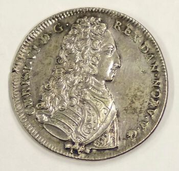 Bortsett fra på slutten av 1700-tallet ble det nesten ikke preget dalere i Norge i dette århundret. Den største mynten var 4 mark, det vil si 64 skilling. Bildet viser likevel en daler med Christian VI (1699–1746) fra 1733. Men det er en ganske spesiell daler, en såkalt reisedaler slått i København for bruk under kongens reise i Norge. Det ble preget slike dalere for alle kongene på 1700-tallet, og de hadde gjerne omskrift med mye skryt av nordmennene. Det mangler på denne, kanskje på grunn av kongens pietistiske livsholdning. Les mer om penger og finanssystemet på 1700-tallet . Foto: Norges Bank