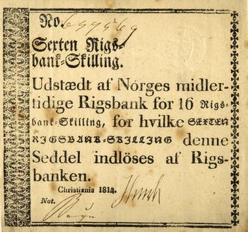 Mens finanssystemet vaklet laget den midertidige riksbanken sedler av forskjellig format. Her ser vi en skillingsseddel med påskriften: «Udstædt af Norges midlertidige Rigsbank for 16 Rigsbank-Skilling, for hvilke denne Seddel indløses af Rigsbanken. Christiania 1814». Les mer om opprettelsen av Norges Bank i 1816 .&amp;#160;Foto: Anne-Lise Reinsfelt/Norsk Folkemuseum