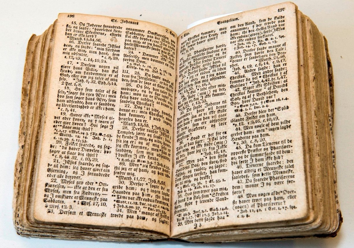 Fargefoto av bok som ligg oppslegen på side 196-197. I toppmargen ser me at dette er evangeliet etter Johannes. Me ser også at dette er eit gamalt trykk på fonten som er brukt og på papirkvaliteten. Sidene er gulbrune i kantane.