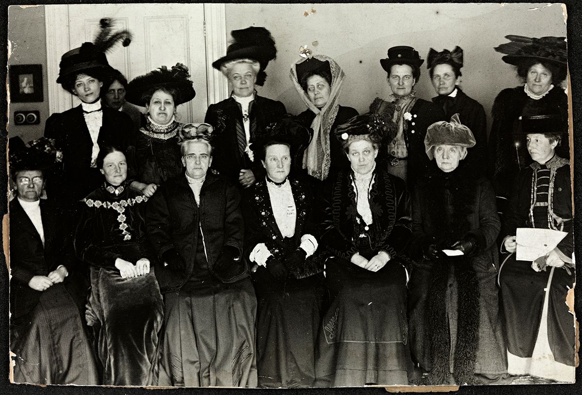 Fotografi av kvinner, fornemt kledd, i to rader. Sittende nest ytterst til høyre er Fredrikke Marie Qvam