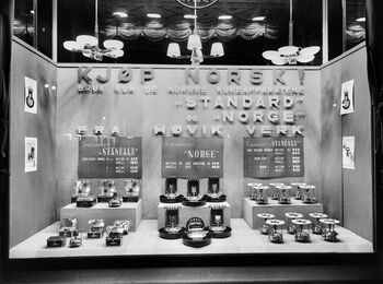 Utstillingsvindu med oppfordringen «Kjøp norsk!» i Christiania Glasmagasin, fra mellomkrigstiden. Les mer om hvordan nordmenn forholdt seg til utlandet i mellomkrigstiden, og hvilket utland som var relevant . Foto: Oslo Museum/ CC BY-SA