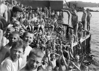 At man skulle bade uten klær var «regelen» for gutter og menn fram til 1920-årene. Her ser vi badende gutter ved badeanlegget ved Akershusstranden rundt 1915. Les mer om da nordmenn begynte å bade . Foto: Johannes Holmsen/Oslo museum/ CC BY-SA
