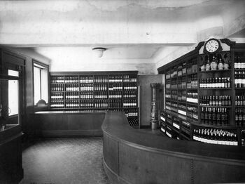 Her er et interiør i et polutsalg fra 1920-tallet. Fotografiet er tatt i Bogstadveien 40, Oslo, ca. 1926. Les mer om etableringen av Vinmonopolet i Norge . Foto: Vinmonopolets arkiv