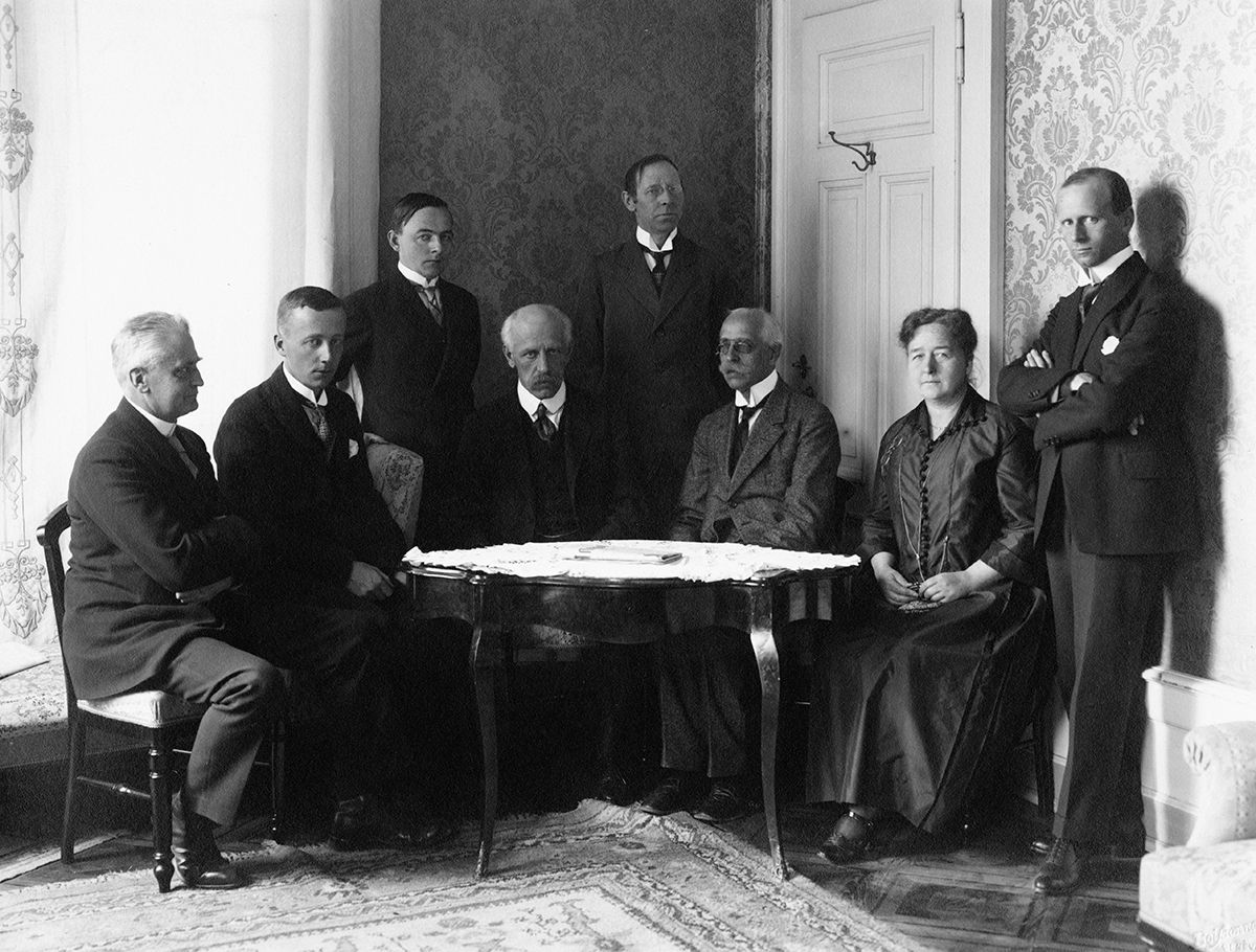 Fotografi av delegasjonen til Folkeforbundets møte i 1921, fotografert rundt et bord, i hjørnet av en stue