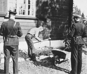 Biskop Eivind Berggrav ble internert på sin egen hytte i Asker, inntil han rømte i april 1945. På dette bildet fra 1942 arbeider han under politioppsyn. Les mer om kirkens motstandskamp under krigen . Foto: NTB scanpix