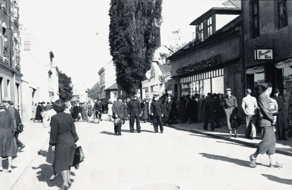 Dette bildet viser Nedre torggate i Drammen 11. juli 1942 like før kl. 9. Vinmonopolet ligger til venstre i gaten. Bilde 1 av 2. Foto: ukjent/Drammens tidendes arkiv