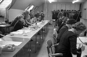 Telefonsalg av trykk laget av kjente norske kunstnere i forbindelse med TV-programmet Vi går ombord , juleaften 1968. Inntektene fra telefonsalget gikk til oppbyggingen av Konvoibyen i Risør. I bakgrunnen til høyre ser vi Erik Bye og Ivar Aaserud som har tatt en pause fra telefonen. Les mer om krigsseilerne og deres oppreisning etter krigen . Foto: Dagbladet/Norsk Folkemuseum/ CC BY-NC-ND