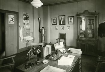 Ett av Trondheim Fattigvesens kontorer i oktober 1942. Ved inngangsdøren og over vasken henger rekrutteringsplakater til Den norske legion. Som offentlig kontor var Fattigvesenet pålagt å sørge for at denne type propaganda- og rekrutteringsplakater ble synliggjort i lokalene sine. Les mer om nordmenn i tysk krigstjeneste . Foto: Schrøder/Trondheim byarkiv/ CC BY