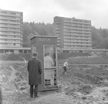 Kø utenfor telefonkiosken ved de nye boligblokkene ved Bogerud en sommerdag i 1964. At det dannet seg kø utenfor telefonkioskene i Norge var vanlig til langt ut på 1980-tallet, men i drabantbyene, der svært mange mennesker i lang tid delte få telefoner, var køen regelen snarere enn unntaket. Les mer om da Oslo fikk drabantbyer . Foto: Dagbladet/Norsk Folkemuseum/ CC BY-NC-ND