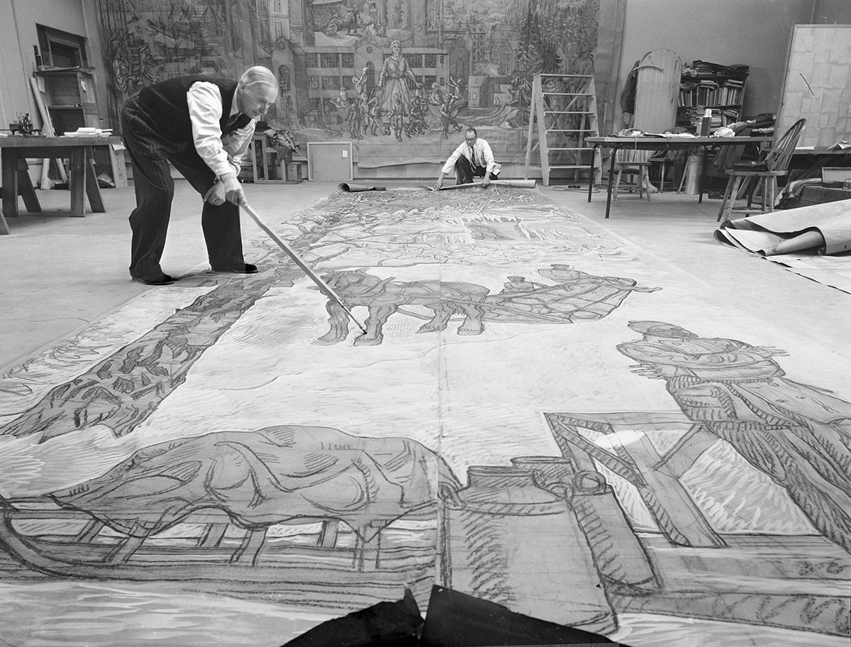 Fotografi som viser kunstneren Per Krohg i ferd med å male på et utrullet lerret, mange meter langt