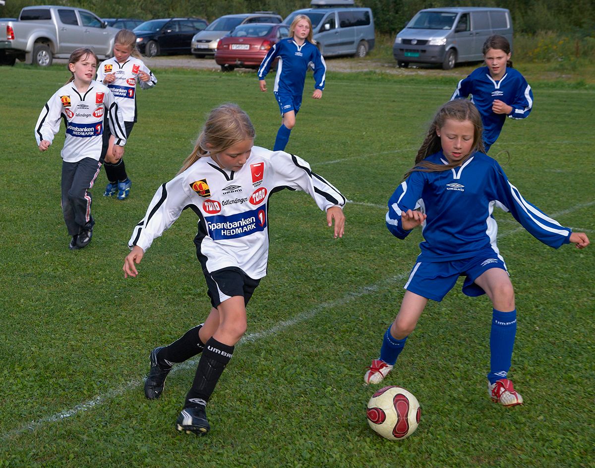 Fotografi av jenter som spiller fotball, iført lagtrøyer
