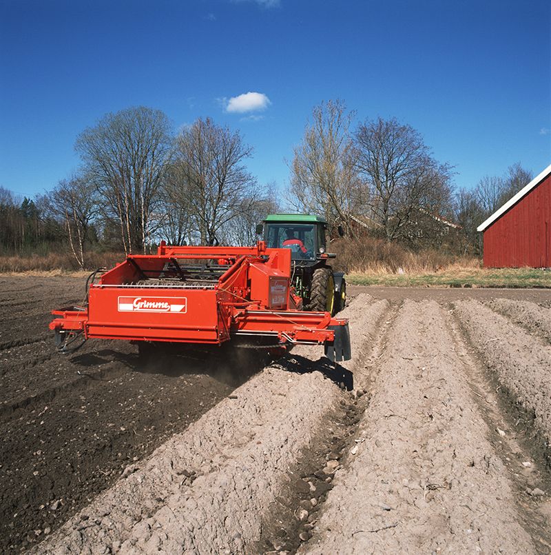 Fotografi som viser en strenglegger-maskin i aksjon: en maskin for å bearbeide jorda før poteter dyrkes