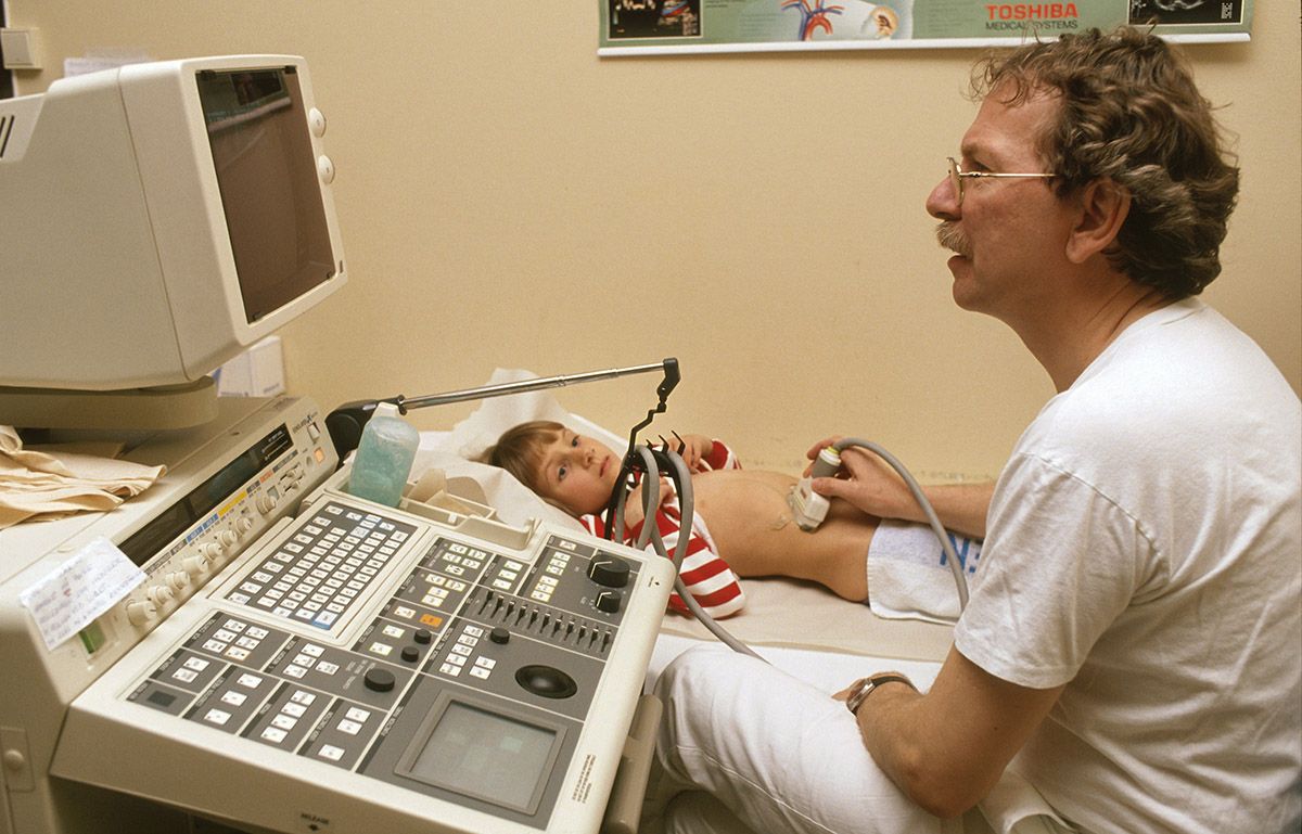 Fotografi av lege som bruker ultralydmaskin for å undersøke et barn