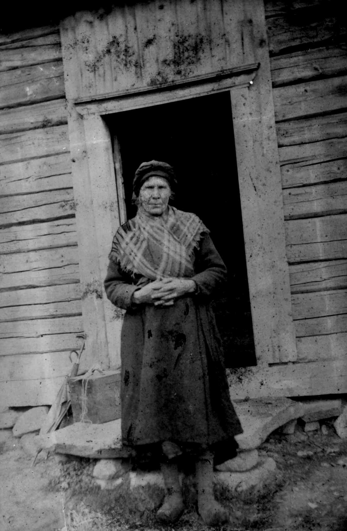 Bildet viser en dame forran et hus i telemark på 1880-tallet