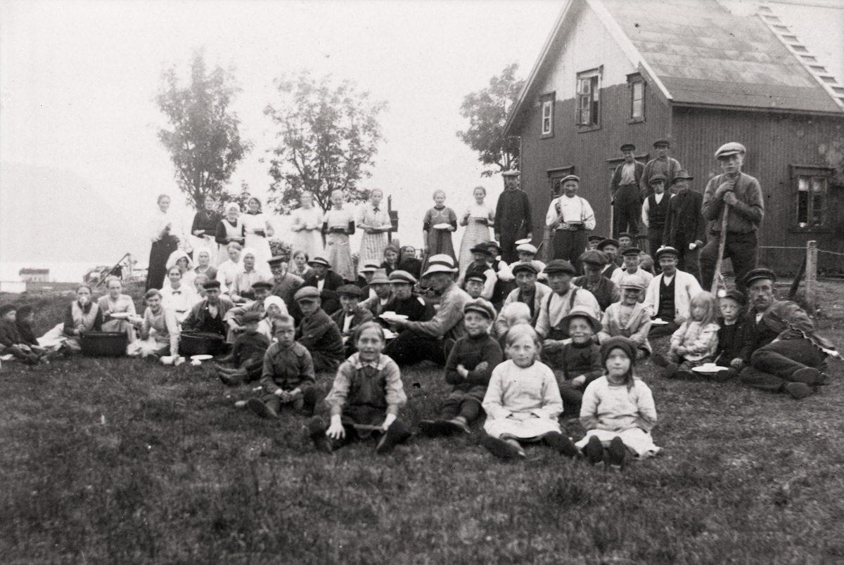 Bildet viser barn og voksne på gresset. De voksne står med tallerken i hendene.