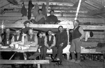 Tømmerdrivere med kokke i felleshusholdningskoie i Bangsjø i Snåsa i 1913. Foto:&amp;#160; Five, Arne Karelius / Anno Norsk Skogmuseum.