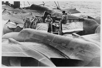 Skip fullastet med våpen på vei over Atlanteren. Her er hele dekket fult av fly. Merk kanonen med vakten midt i bildet. Fra en konvoitur høsten 1941.&amp;#160;