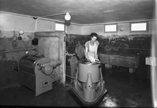 En kvinne vasker klær i vaskekjelleren i 1951. Bildet er tatt i det hun legger klær i sentrifugen. Foto: Wilhelm Rager. Eier: Oslo Museum.