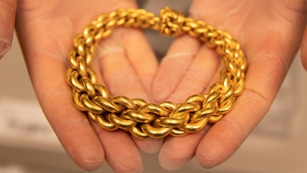 armring i gull ligger i to hender
